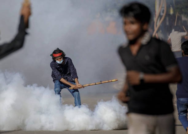An Anti-quota student protester in the middle of teargas as