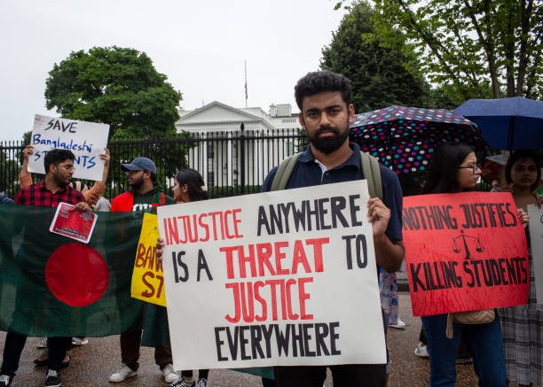 A demonstrator holding a protest sign with Injustice