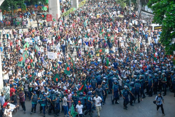 A crowd of protesters marches with flags, placards and