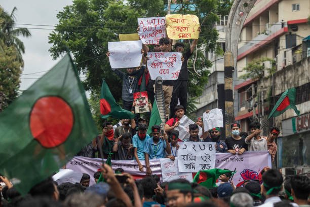 Protesters hold placards and a banner while chanting slogans