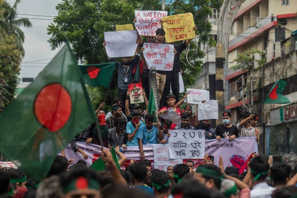 Protesters hold placards and a banner while chanting slogans