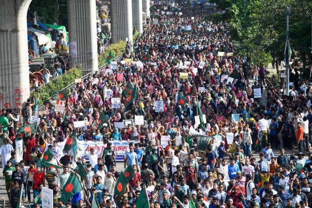 A crowd of protesters marches with flags, placards and